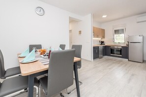 Cozy living space with a dining area and kitchenette, featuring a table, chairs, stove, oven, and refrigerator.