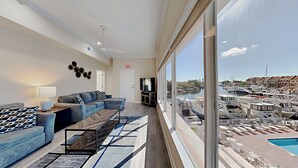 A spacious living room with a large window overlooking a marina.