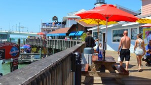 A pier with a wooden deck, a lifeguard tower, and a boat docked in the background.