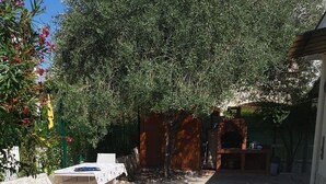 Un patio esterno con pavimento in pietra, un tavolo con tovaglia bianca e un forno a mattoni.
