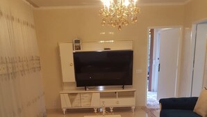 Un soggiorno con televisore, divano e lampadario.
