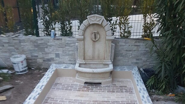 Un patio lastricato con una fontana in pietra e un cordolo in mattoni.
