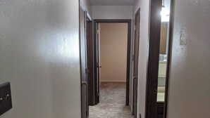 A narrow hallway with carpeted floors and wooden doors. - Wonderfully located two bedroom apartment (Pierre)