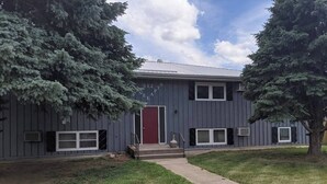 A two-story building with a red door, multiple windows, and a small front porch. - Wonderfully located two bedroom apartment (Pierre)