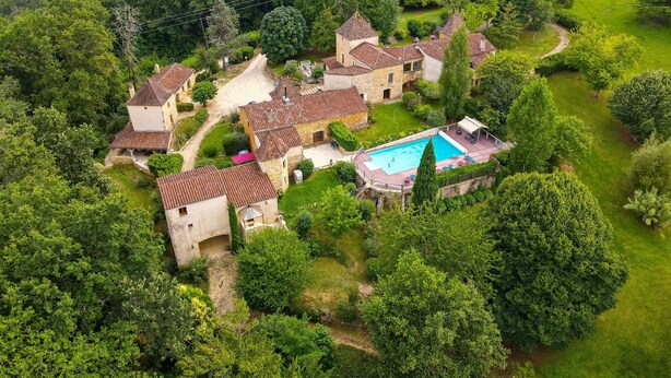 An aerial view of a property with multiple stone buildings, a swimming pool, and lush greenery. - A house of character (Puy-l'Évêque)