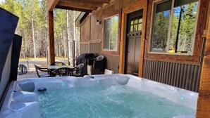 A hot tub in a wooden cabin with a view of trees.