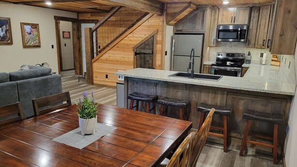 A modern kitchen with wooden cabinetry, a stainless steel refrigerator, and a granite countertop.