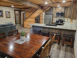 A modern kitchen with wooden cabinetry, a stainless steel refrigerator, and a granite countertop.