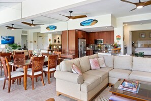 A spacious living area with a large beige sectional sofa, wooden dining table with chairs, and a kitchen area with wooden cabinets and stainless steel appliances. - New Listing: Spacious 2-bedroom Luxurious Kapalua Golf Villa (Lahaina)