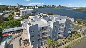 Un immeuble résidentiel à plusieurs étages, doté de balcons, d’une piscine et offrant une vue sur la côte.