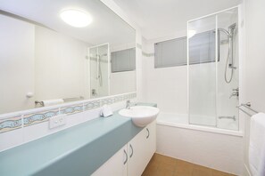 Une salle de bain moderne avec un grand miroir, un lavabo, une cabine de douche et une baignoire.