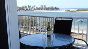 Un balcon avec une table et des chaises, donnant sur une plage et offrant une vue sur la ville.