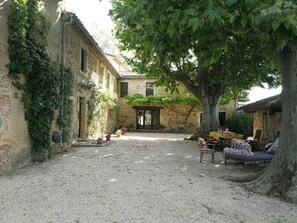 Ein Innenhof mit Kiespflaster, einem Baum und einem Gebäude mit Tür und Fenstern.
