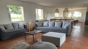 Un soggiorno moderno con un divano, poggiapiedi, un tavolino da caffè e, sullo sfondo, un angolo cottura.