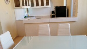 A modern kitchen with white cabinets and a glass table.