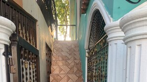 A staircase with patterned tiles leading up to a door with ornate metal gates.