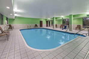 Una piscina interna con pavimento piastrellato, sedie e una porta che dà su un'altra stanza.
