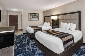 A hotel room with two beds, a TV, a framed picture on the wall, and a patterned carpet.