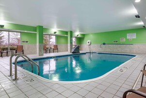 An indoor swimming pool with clear depth markers, a tiled floor, and green walls.