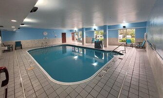 Una piscina interior con suelo de baldosas, un reloj en la pared y un cartel que indica prohibido bucear.