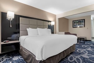 Una habitación de hotel con una cama grande, mesitas de noche, un escritorio y una silla.