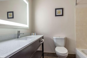 Ein Badezimmer mit weißem Waschbecken, Spiegel, Toilette und gerahmten Bildern an der Wand.