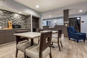 A modern hotel lobby with a reception desk, seating area, and a microwave on a counter.