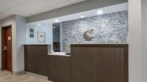 A reception desk with a mosaic wall, a wooden floor, and a door to the left. - Comfort Inn & Suites Liverpool - Syracuse (Liverpool)