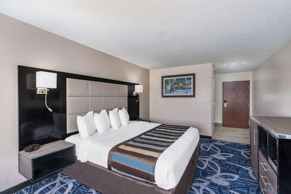 A hotel room with a bed, a flat-screen TV, a desk, and a door. - Comfort Inn & Suites Liverpool - Syracuse (Liverpool)