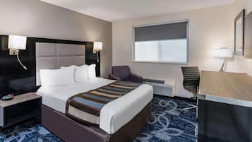 A hotel room with a bed, a desk, a chair, a TV, and a window.