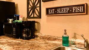A kitchen counter with a coffee maker, a bottle of dish soap, and a sign that reads "EAT - SLEEP - FISH". - #3 Uncertain Oasis-Uncertain Lodge and Inn (Karnack)