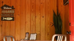 A wooden wall with a welcome sign and a fish sign. There are two metal chairs and a small table with a sign. A potted plant is on the right. - #3 Uncertain Oasis-Uncertain Lodge and Inn (Karnack)