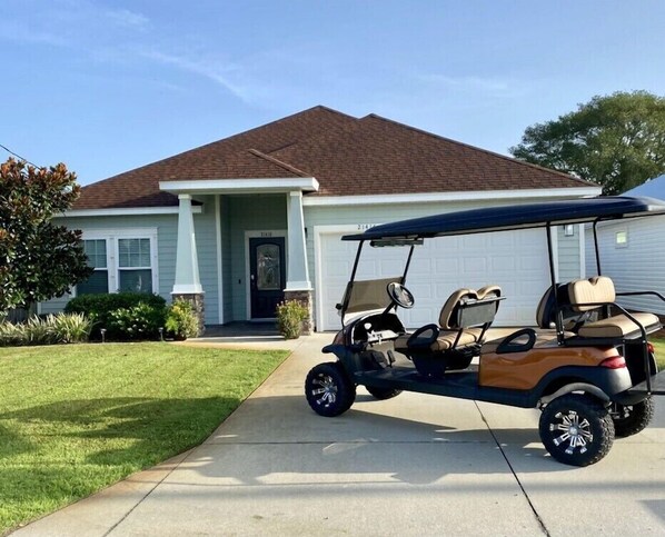 Une maison d’habitation avec un garage et une voiturette de golf garée devant.