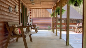 Een overdekt terras met houten banken en een gebouw op de achtergrond.