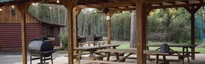 A rustic outdoor pavilion with picnic tables and a barbecue grill.