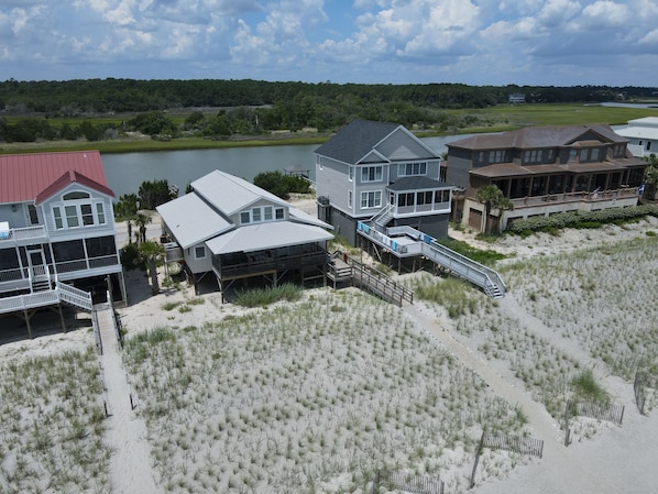 A coastal property with multiple buildings, including a large house with a covered porch and a smaller structure with a balcony.