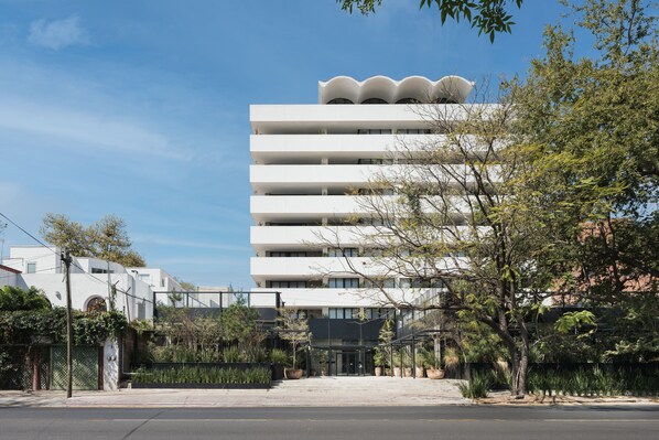 Un edificio de varios pisos con un diseño arquitectónico moderno, que cuenta con una serie de balcones y una estructura de techo distintiva.