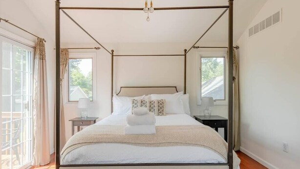A four-poster bed with a canopy, bedside tables, and a view of the outdoors.