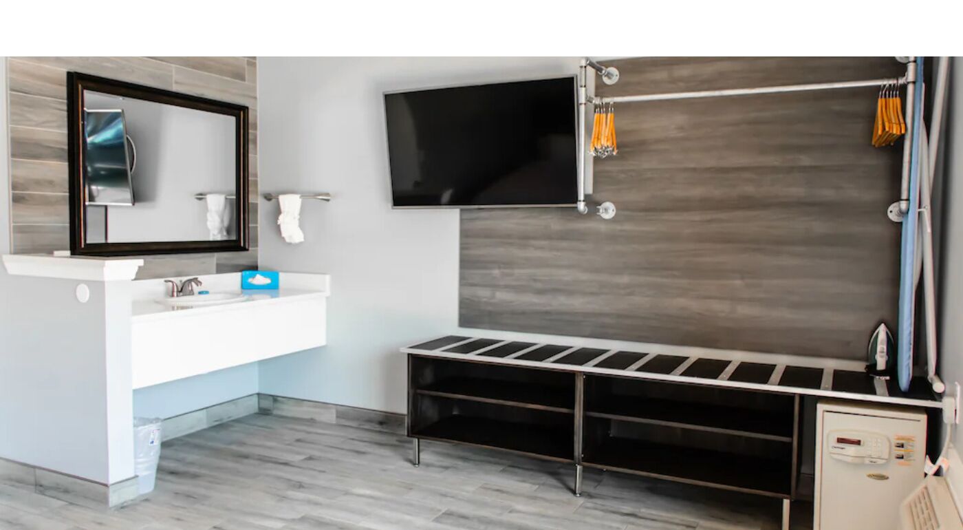 A modern bathroom with a large mirror, a flat-screen TV, a shower area, and a built-in bench.