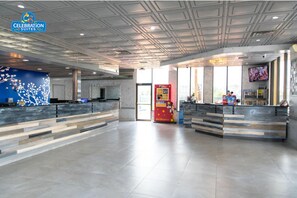 A spacious hotel lobby with two reception desks, a large window, and a ceiling with a geometric pattern. - Celebration Suites - 2 Miles from Disney - For 6 (Kissimmee)