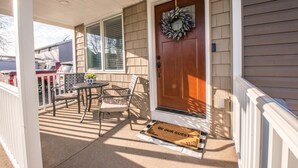 A front porch with a wooden door, a welcome mat, and a small table with chairs. - KING Master En-Suite- BRAND NEW Home- Buffalo's Best Kept Secret! (Buffalo)