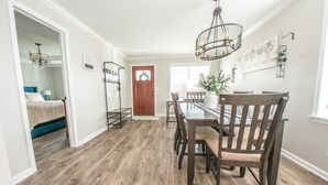 A dining area with a wooden table and chairs, a chandelier, and a door leading to another room. - KING Master En-Suite- BRAND NEW Home- Buffalo's Best Kept Secret! (Buffalo)