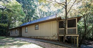 A single-story building with a porch, a stone foundation, and a sloped roof.