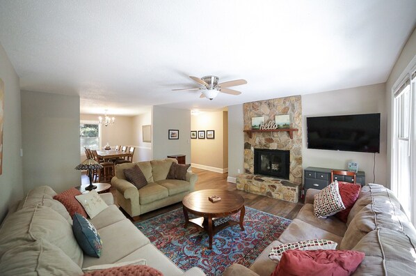 A living room with a fireplace, a ceiling fan, and a television.
