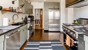 A modern kitchen with stainless steel appliances, a black and white striped rug, and wooden flooring.