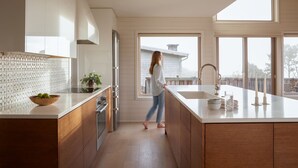 A modern kitchen with wooden cabinets, a large island, and a view to the outside. - Suil Na Mara - Modern Home with Mountain and Ocean Views (Tillamook County)