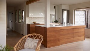 A modern kitchen with a wooden island, white cabinets, and a large window. - Suil Na Mara - Modern Home with Mountain and Ocean Views (Tillamook County)