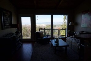 Relax in this inviting living space with a sofa, coffee table, and side table, plus a balcony with a view of the surrounding landscape.