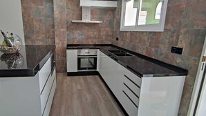 Cozinha moderna com armários brancos, bancada preta e forno embutido.