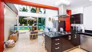 Una cocina moderna con una isla central, un comedor con asientos exteriores y vistas a una piscina.
